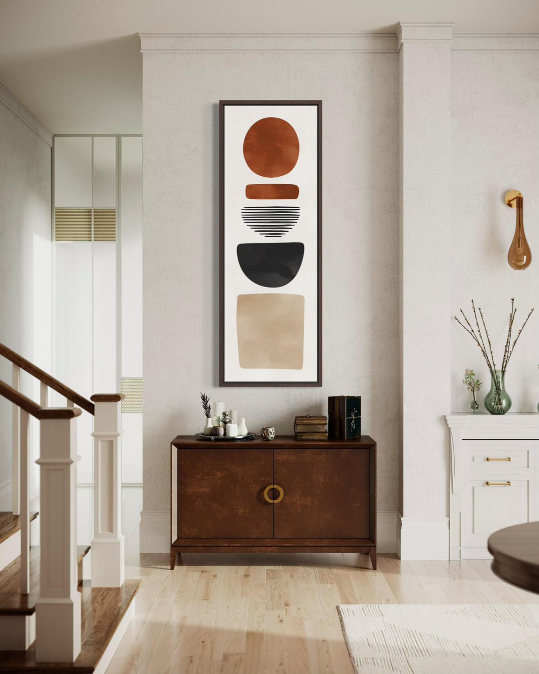 A tall narrow canvas featuring stacked abstract geometric shapes in terracotta, charcoal, and sand.