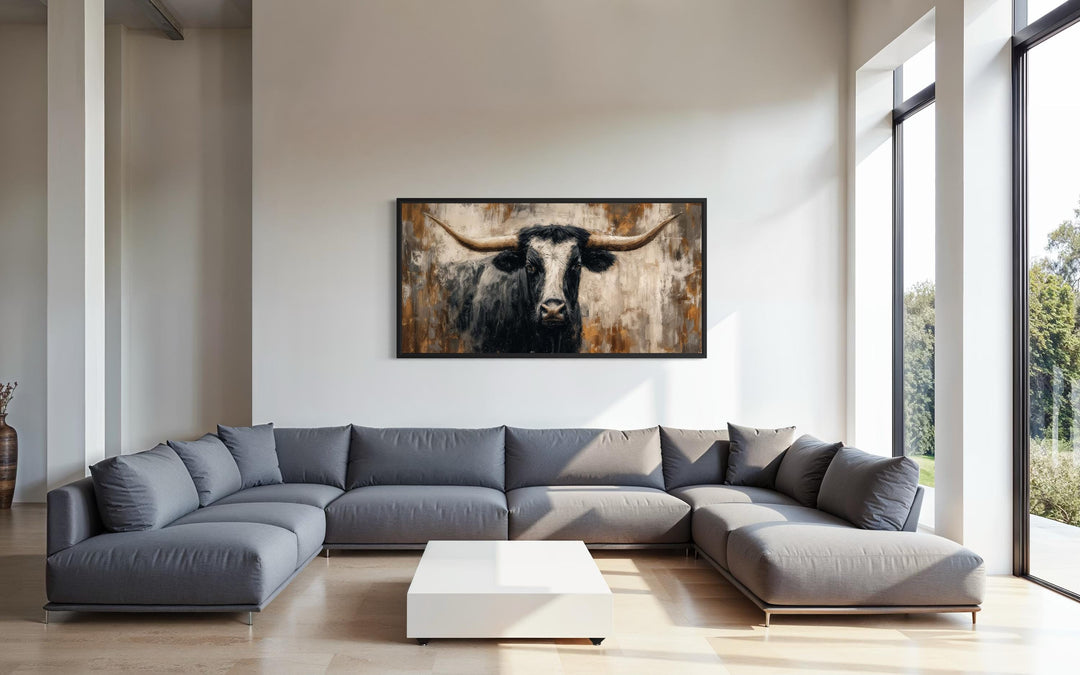 Abstract longhorn bull canvas wall art in a modern industrial living room above a gray sectional.