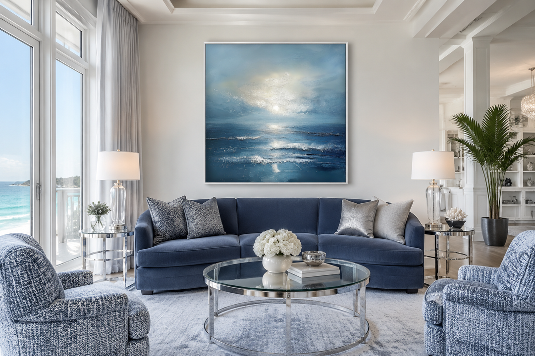 Abstract ocean blue and grey coastal framed canvas wall art hanging above a navy blue sofa.