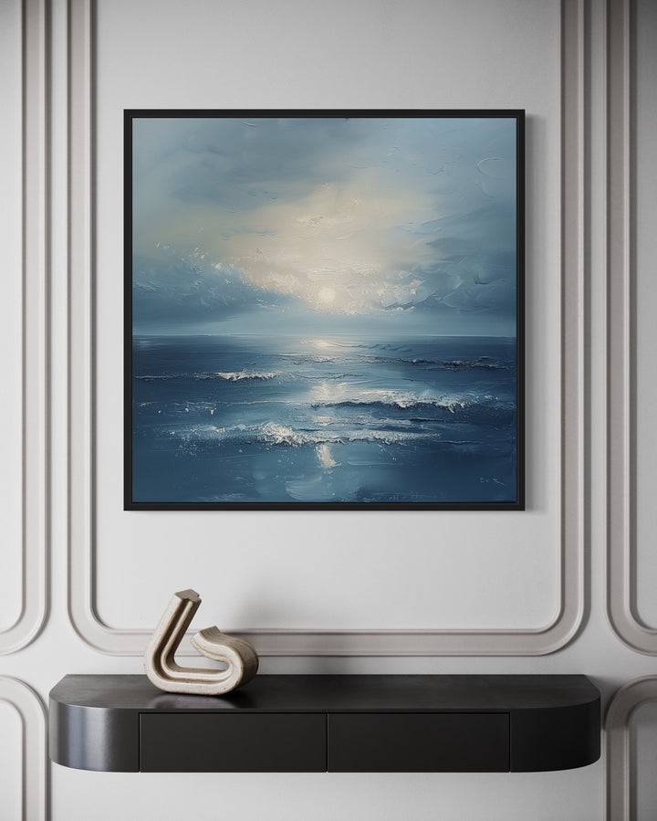 Abstract ocean blue and grey coastal framed canvas wall art above a black console table.