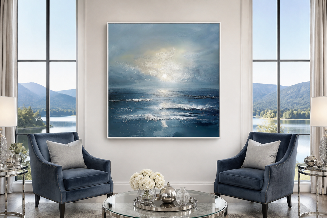 Abstract ocean blue and grey coastal framed canvas wall art above two blue armchairs.
