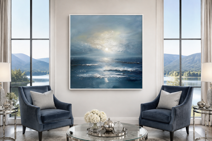 Abstract ocean blue and grey coastal framed canvas wall art above two blue armchairs.