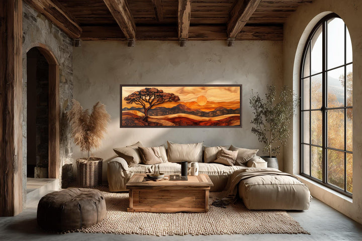 Acacia tree wall art in a wood carving style on a long narrow canvas above a neutral sofa.