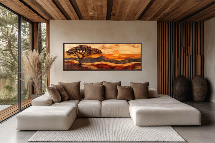 Acacia tree wall art in a wood carving style on a long narrow canvas above a modern sectional sofa.