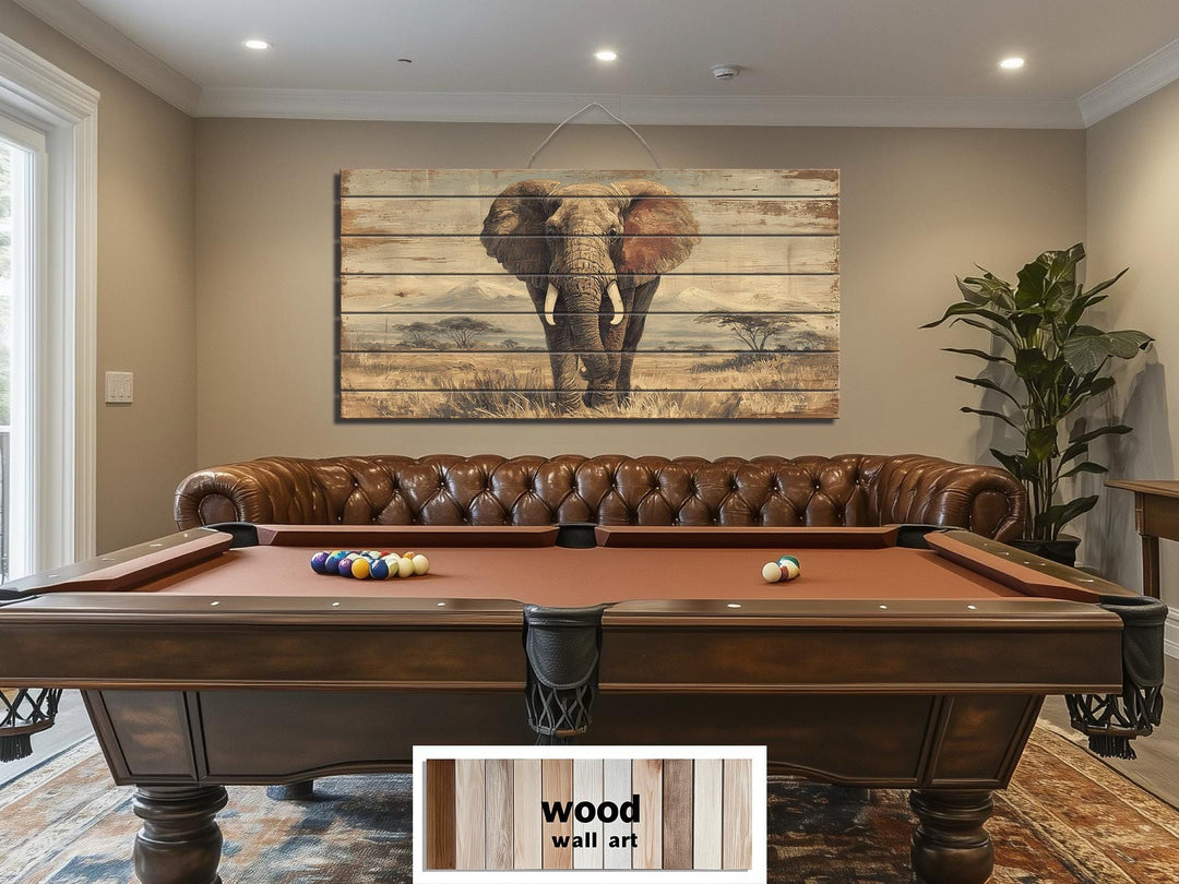 African elephant wall art on distressed wood planks hanging above a pool table in a rustic room.