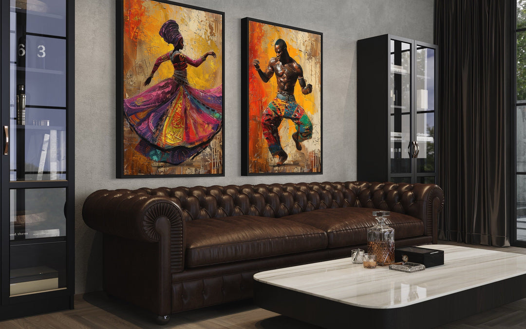 Two framed canvas prints of an African man and woman dancing above a brown leather sofa.