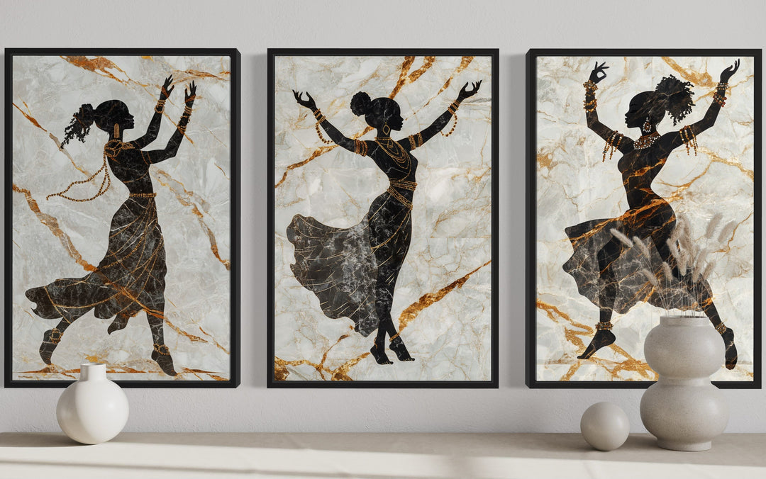 Three-piece framed canvas set of black dancing women silhouettes with gold accents on marble.