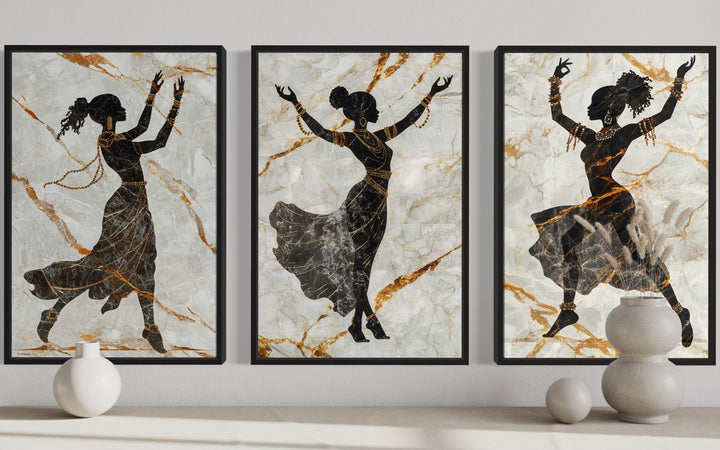 Three-piece framed canvas set of black dancing women silhouettes with gold accents on marble.