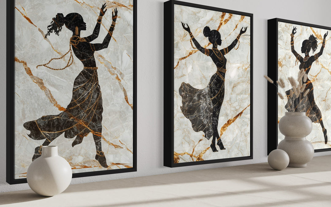 Three-piece framed canvas set of black dancing women silhouettes with gold accents on marble.
