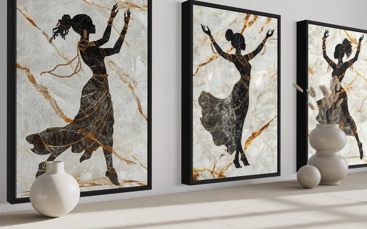 Three-piece framed canvas set of black dancing women silhouettes with gold accents on marble.