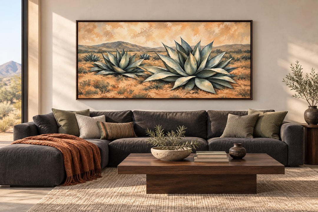 Southwestern agave plants in a golden desert landscape framed canvas wall art above a dark sofa.