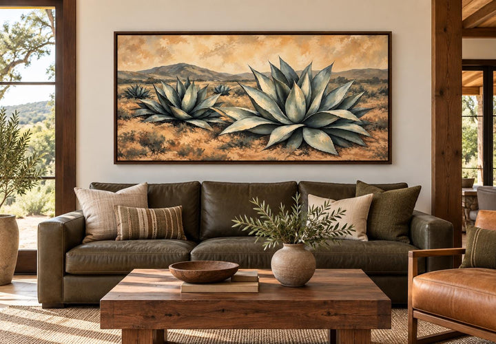Southwestern agave desert landscape framed canvas wall art above a green leather sofa.