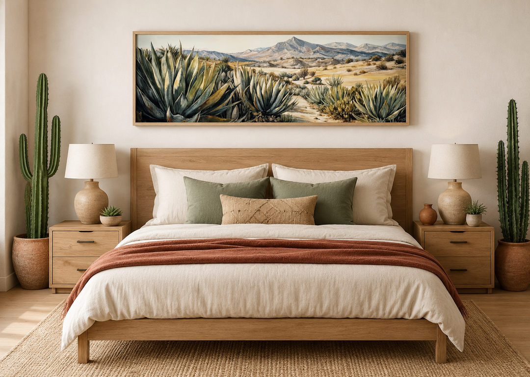 Horizontal framed canvas wall art of agave plants in a desert landscape above a wooden bed.