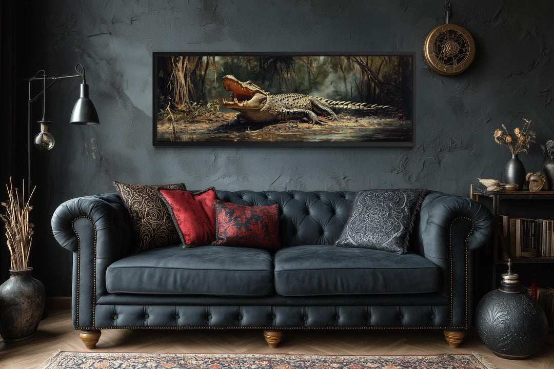 A long horizontal canvas print of an alligator in a swamp hangs above a dark tufted leather sofa.
