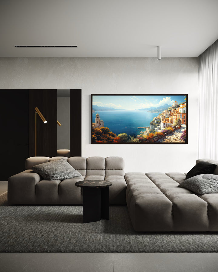 Large framed canvas print of an Amalfi Coast painting hanging above a modern grey sectional sofa.