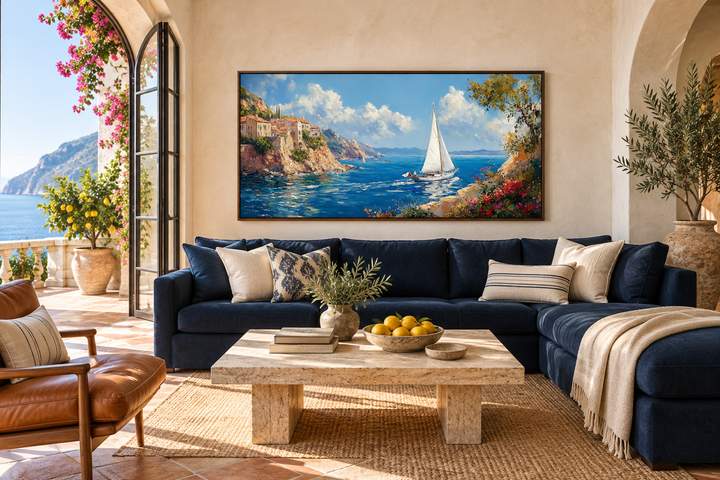 Amalfi Coast with sailboat framed canvas wall art above a navy sofa in a Mediterranean living room.