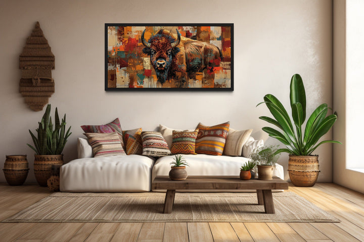 Colorful American Bison canvas print in a black frame above a white sofa with rustic decor.