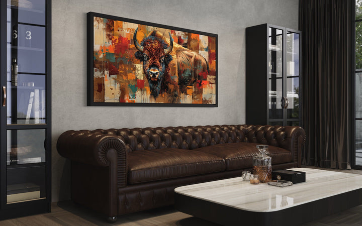 Colorful American Bison canvas wall art hanging above a brown leather sofa in a rustic living room.