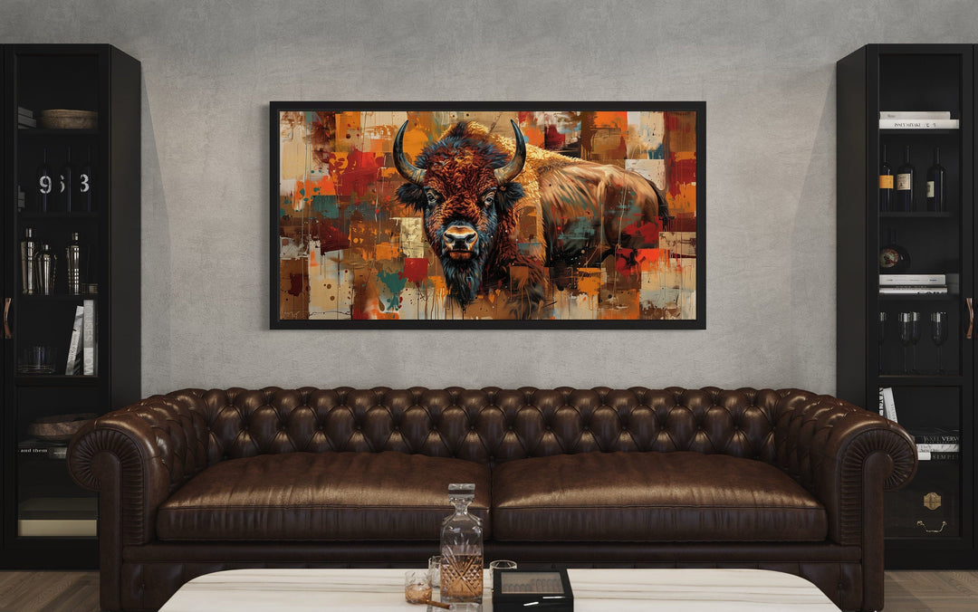Colorful American Bison canvas wall art in a black frame above a brown leather tufted sofa.