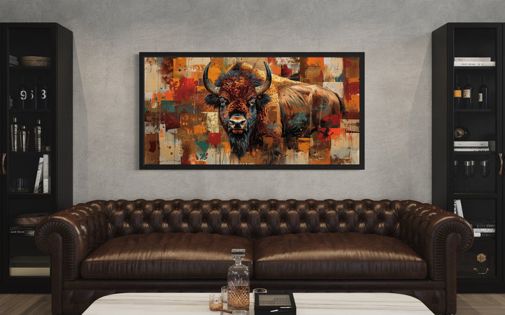 Colorful American Bison canvas wall art in a black frame above a brown leather tufted sofa.