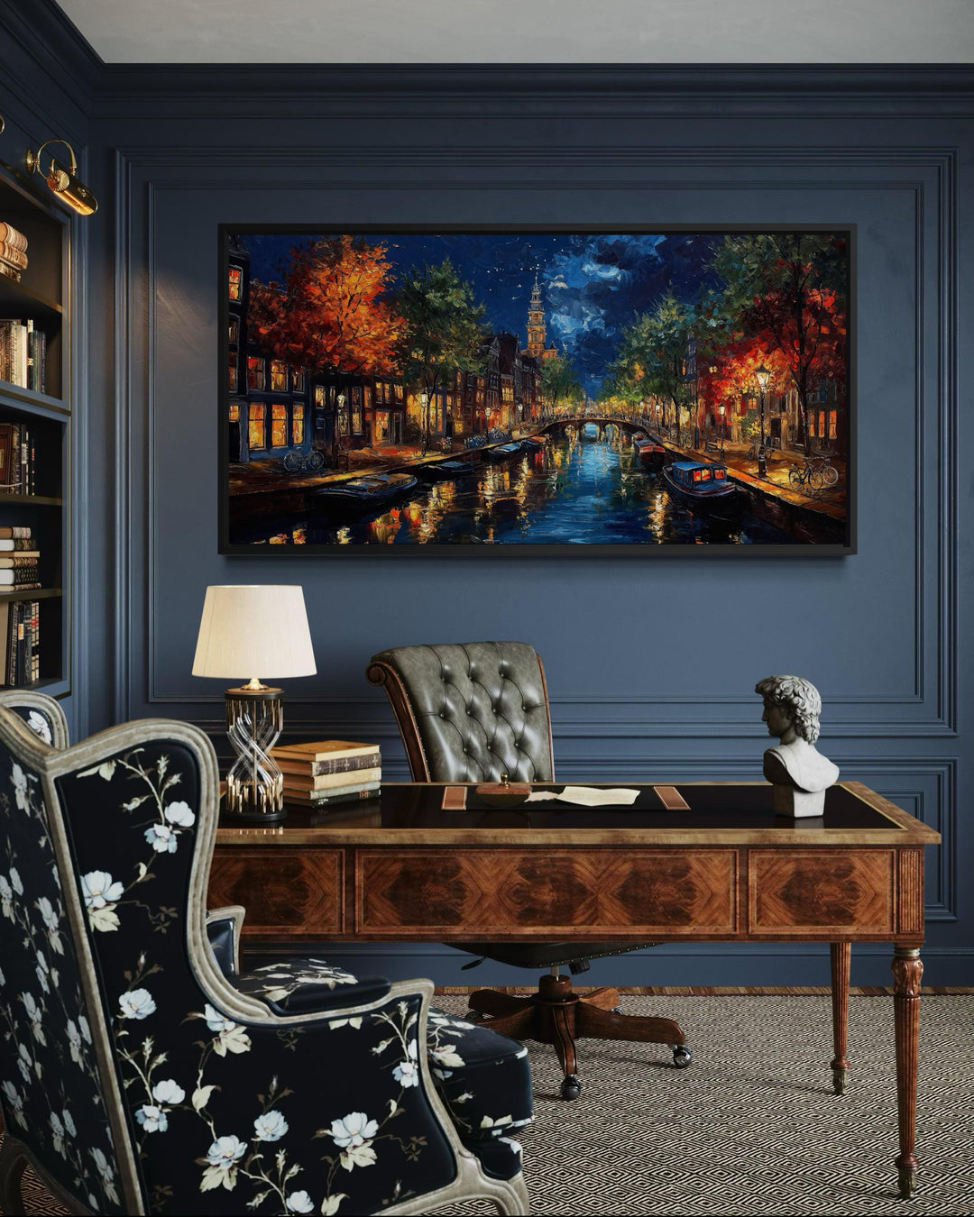 A large horizontal canvas painting of an Amsterdam canal at night hangs in a dark, classic office.