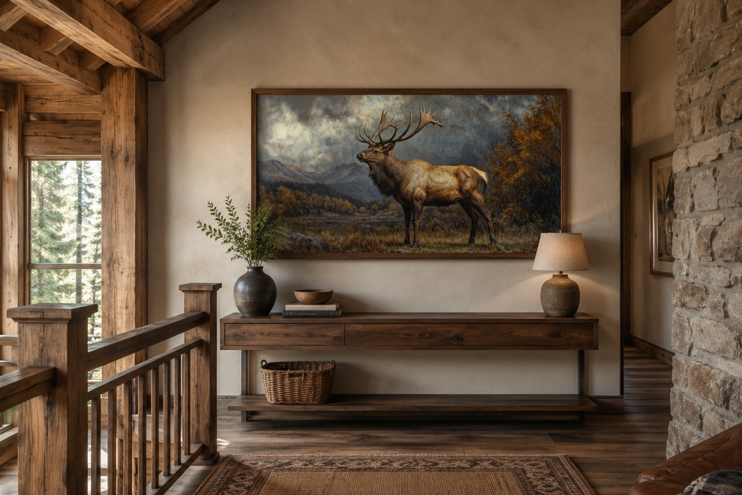 Antique elk in autumn mountains framed canvas wall art above a wooden console in a rustic cabin.