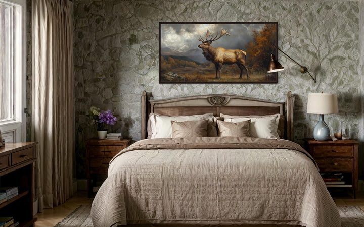 Antique elk in autumn mountains framed canvas wall art hanging above a bed in a rustic room.