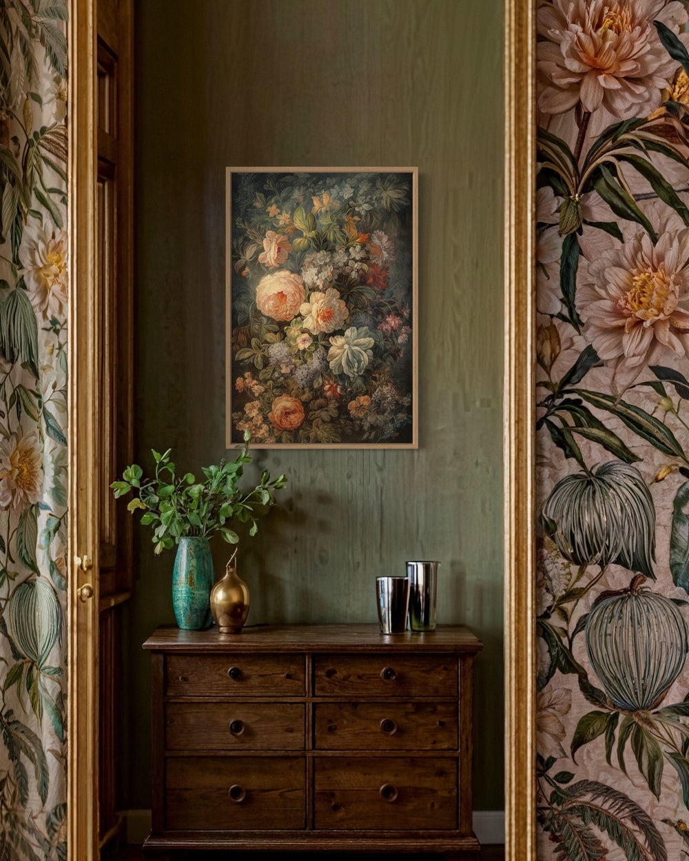 a wooden dresser with a vase of flowers and two cups on top, set against a green wall with a framed painting hanging above it.
