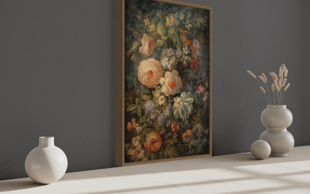 a large floral painting hanging on a gray wall, with two white vases placed on a white surface to the right of the painting.