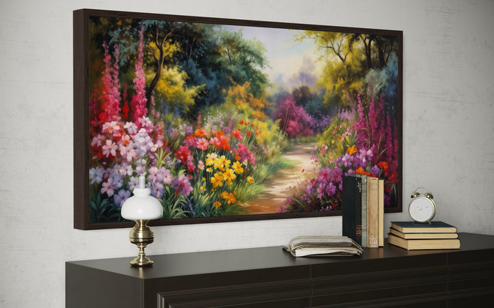 Antique flower garden framed canvas wall art above a dark wood dresser with books and a lamp.