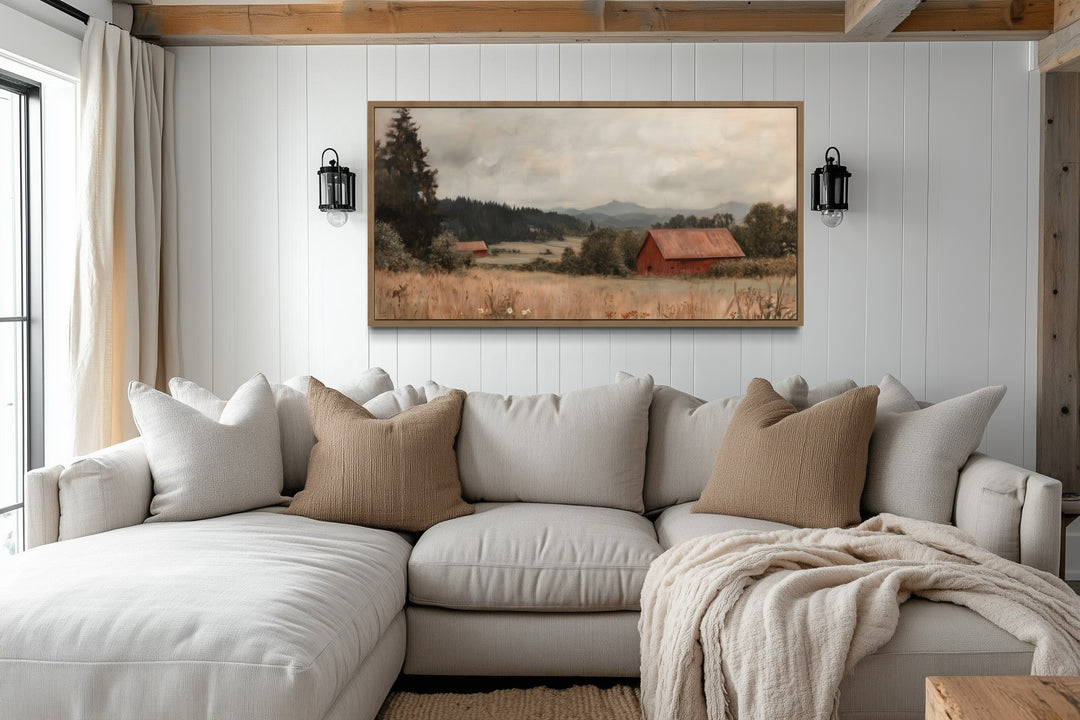 Framed antique red barn canvas print hanging above a neutral sectional sofa in a farmhouse room.
