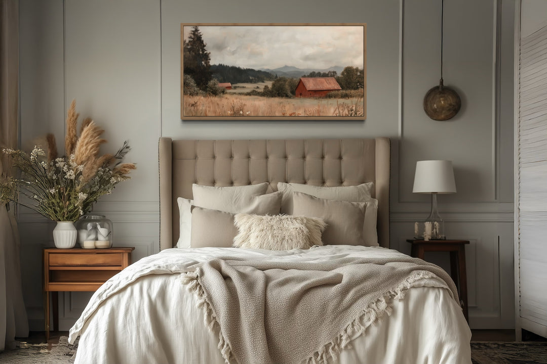 Framed antique red barn canvas print hanging above a bed in a rustic farmhouse style bedroom.