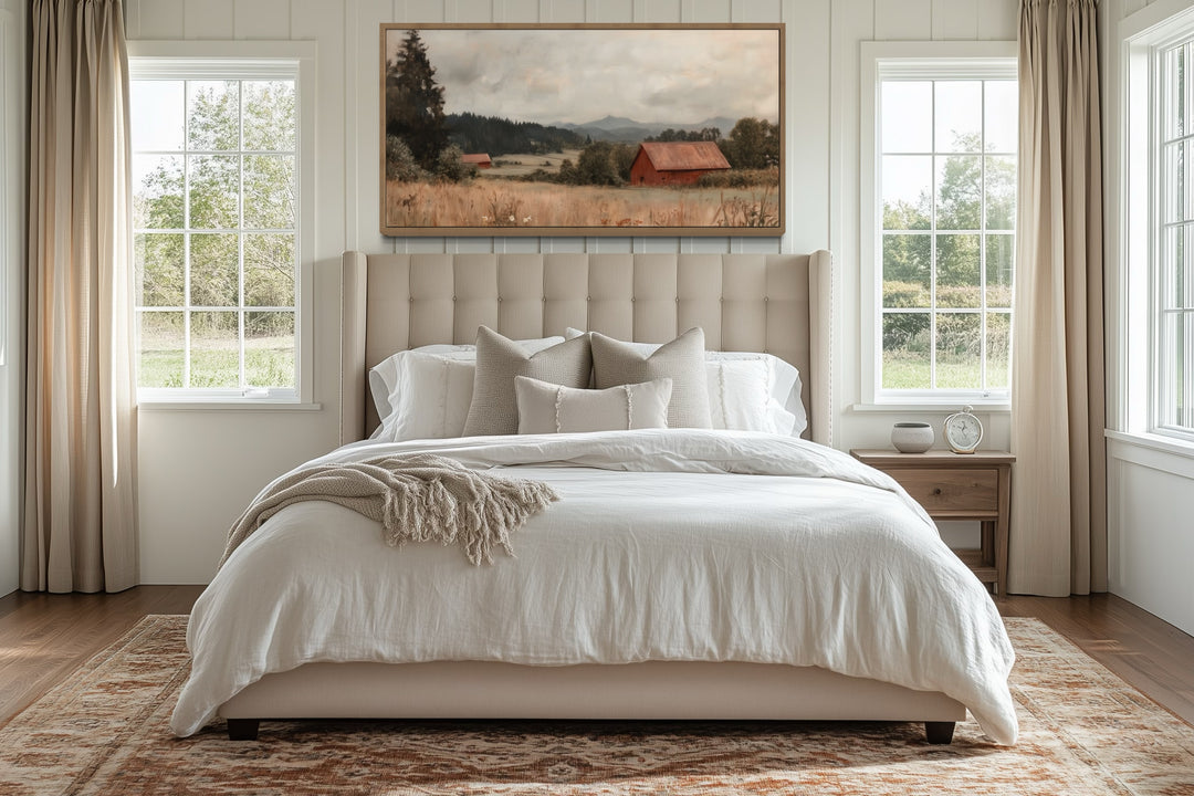 Antique red barn canvas print in a wooden frame hanging above a neutral upholstered bed.