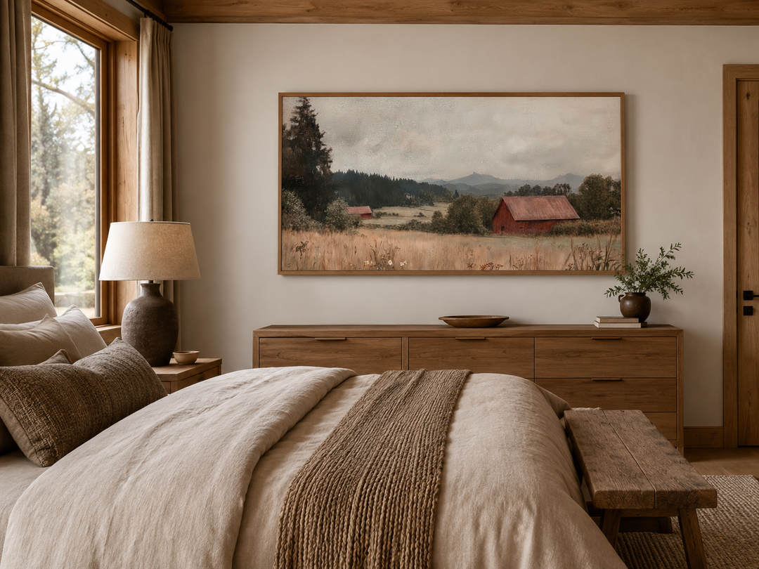 Framed antique red barn landscape painting hanging above a wooden dresser in a rustic bedroom.