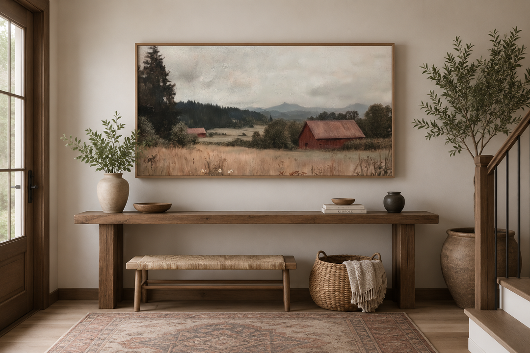 Framed antique red barn canvas print in a rustic entryway with a wooden console and woven bench.