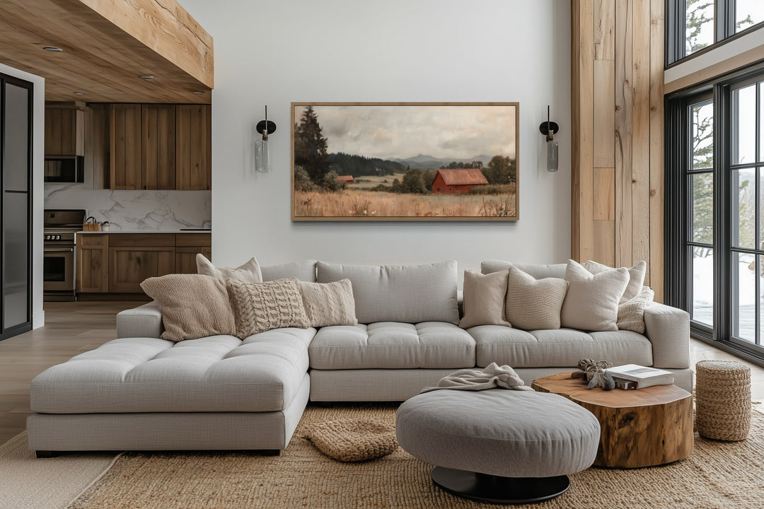 Antique red barn canvas print in a wooden frame hanging above a modern sectional sofa.