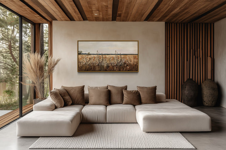Antique rustic wildflowers field framed canvas wall art hanging above a modern sectional sofa.