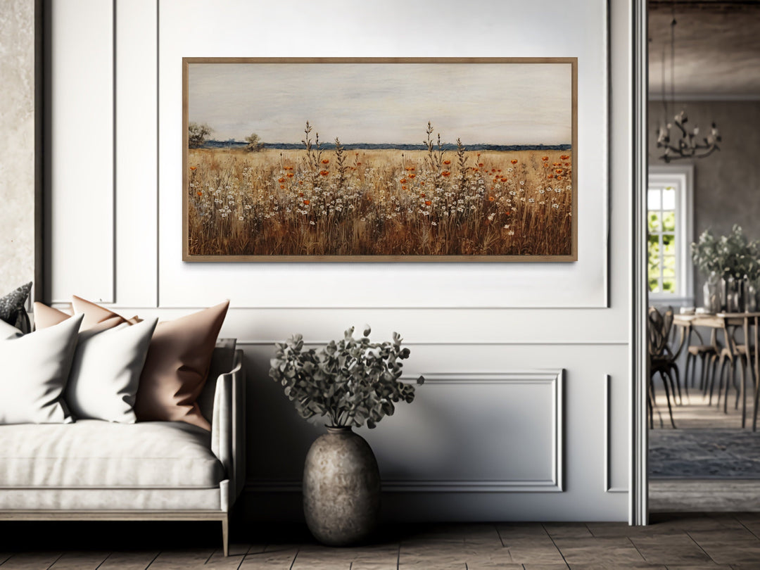 Antique rustic wildflowers field framed canvas wall art hanging above a sofa in a neutral room.