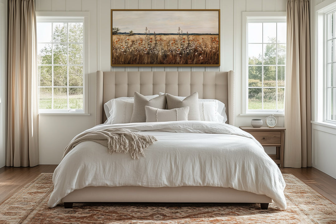 Antique rustic wildflowers field framed canvas wall art hanging above a bed in a neutral bedroom.