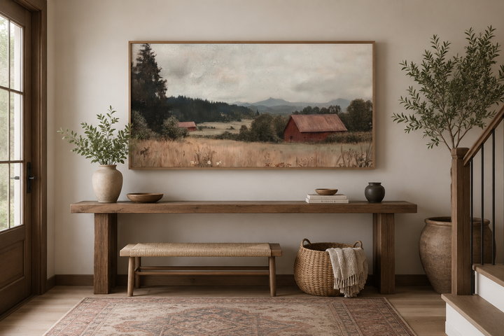 Framed antique red barn canvas print in a rustic entryway with a wooden console and woven bench.