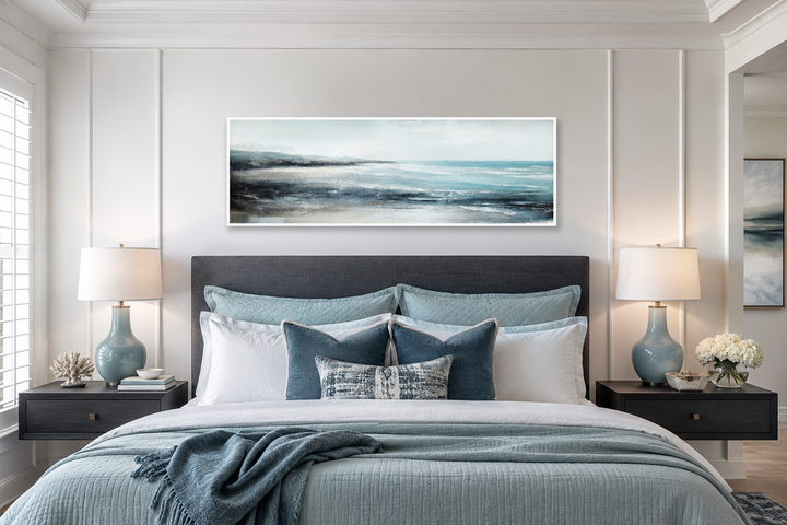 Aqua blue ocean beach coastal framed canvas wall art displayed over a bed in a serene bedroom.