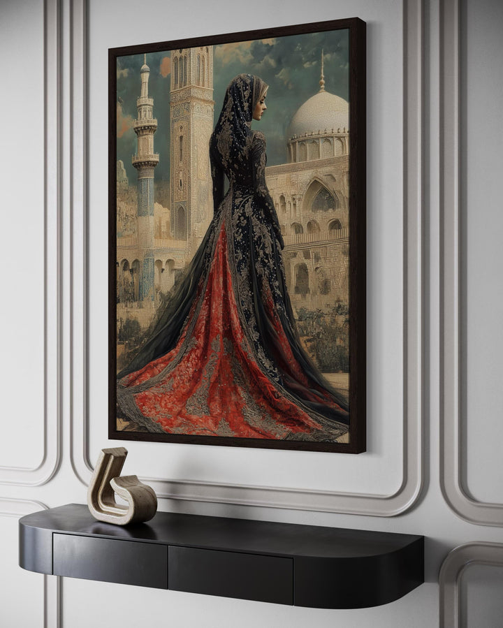 Framed canvas art of an Arabic princess in a red and black dress before a mosque on a white wall.