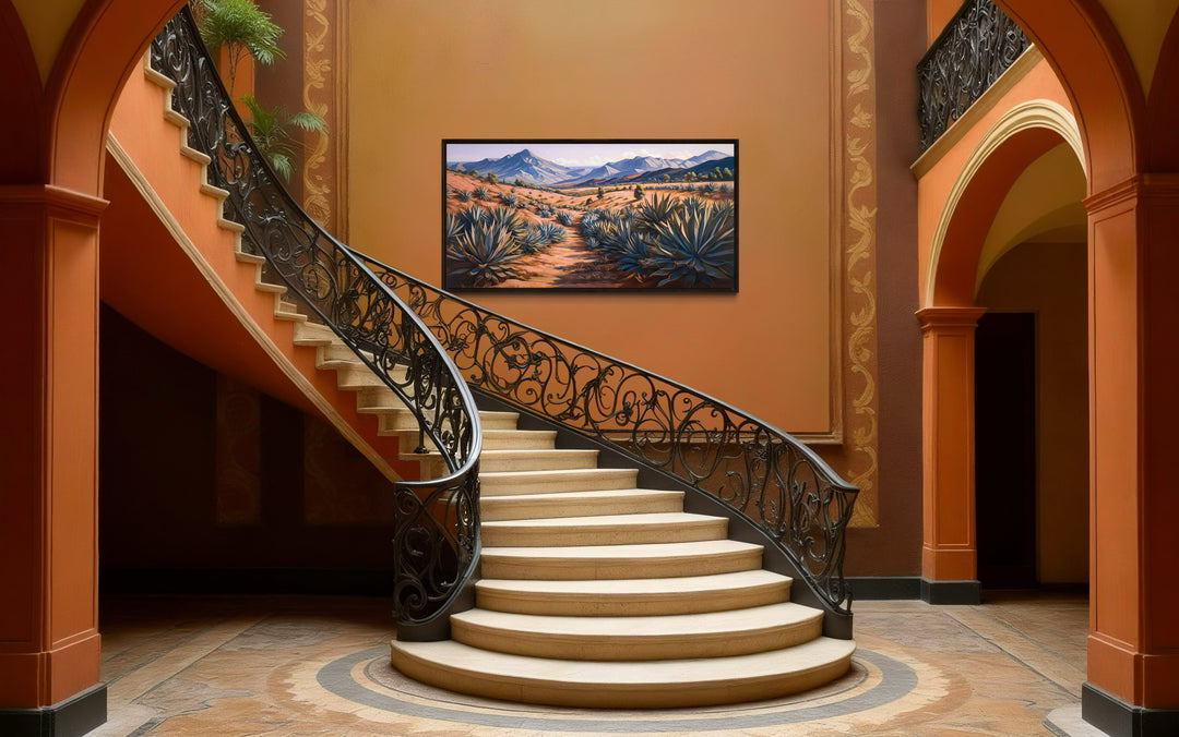 Framed canvas wall art of an Arizona desert landscape with agave plants above a grand staircase.