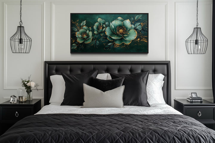 Emerald green and gold floral canvas print centered above a black tufted headboard in a bedroom.