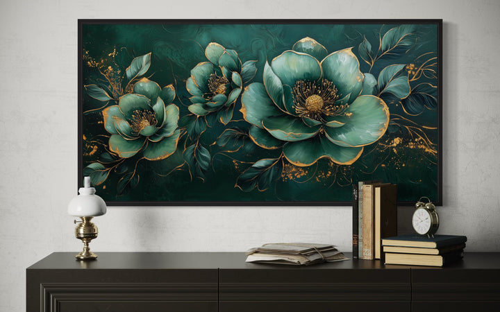 Emerald green and gold floral canvas print in a black frame above a dark wood sideboard.