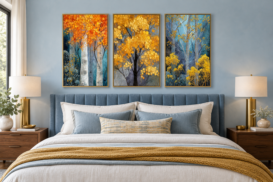 Three-piece autumn aspen tree wall art set in gold frames above a blue upholstered bed.