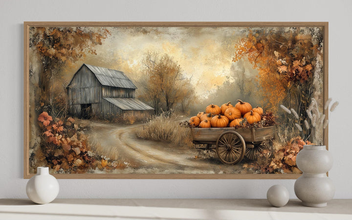 Autumn barn and pumpkin cart farmhouse canvas wall art in a wooden frame on a white wall.
