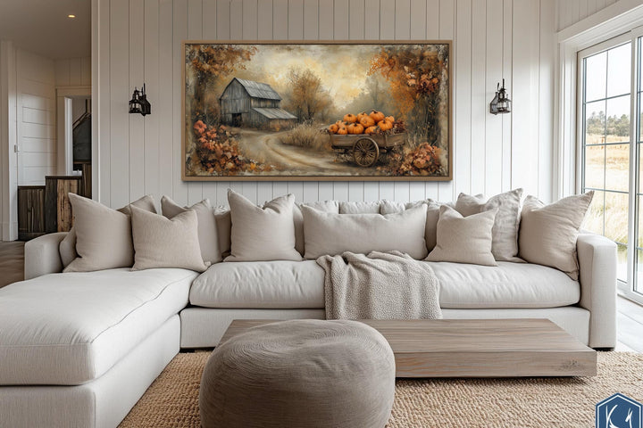 Autumn Barn and Pumpkin Cart farmhouse canvas wall art above a neutral sectional sofa.