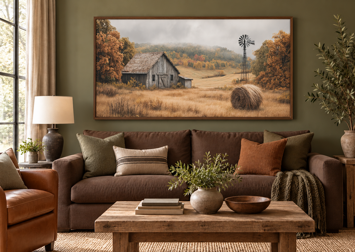 Rustic barn, hay bale, and windmill in a fall landscape canvas wall art above a brown sofa.