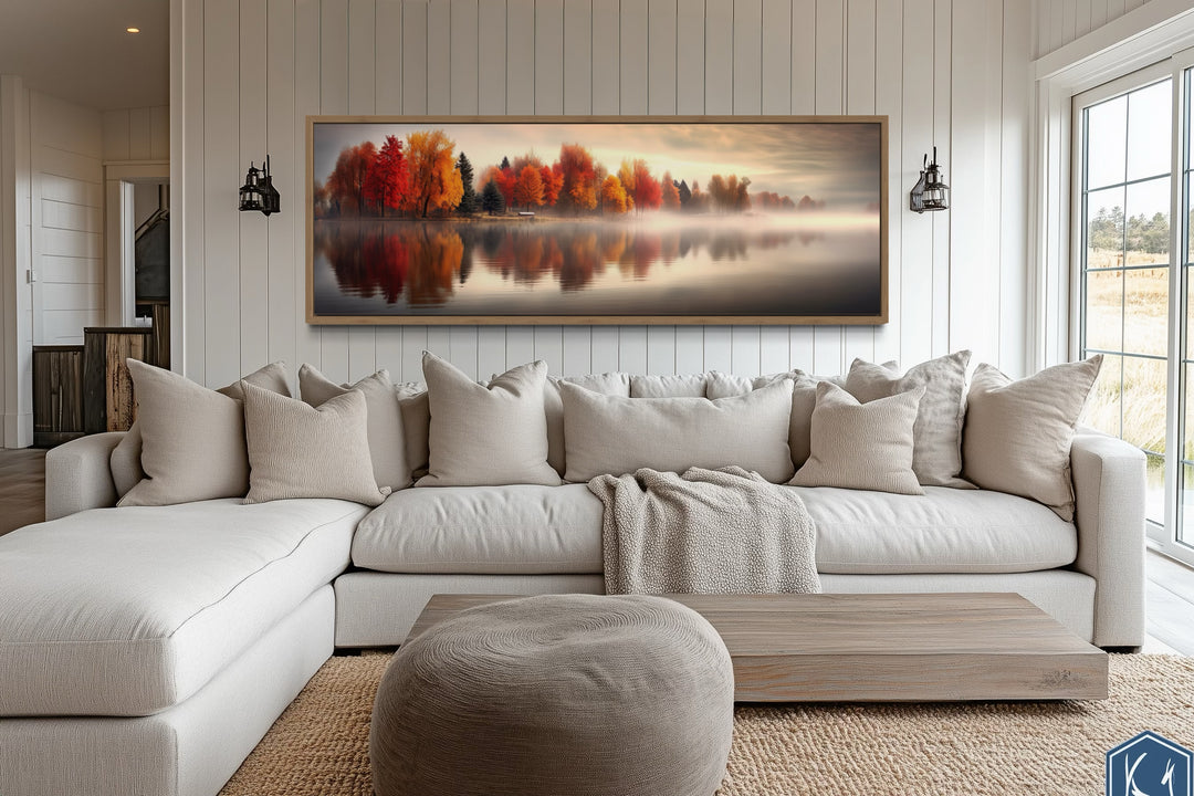 Autumn forest lake reflection long horizontal canvas wall art above a neutral sectional sofa.